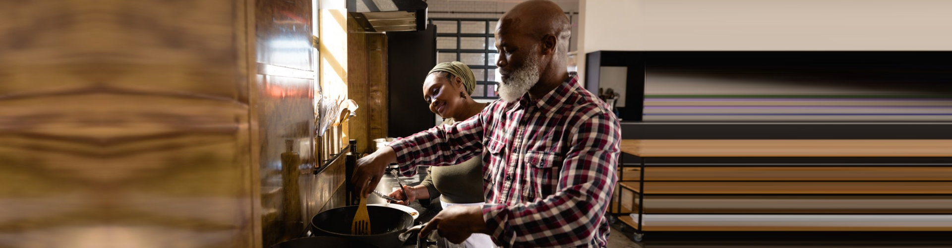 senior man cooking while a caregiver watching